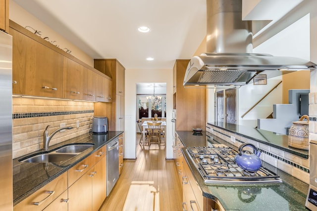 kitchen with sink, dark stone countertops, stainless steel appliances, island range hood, and decorative backsplash