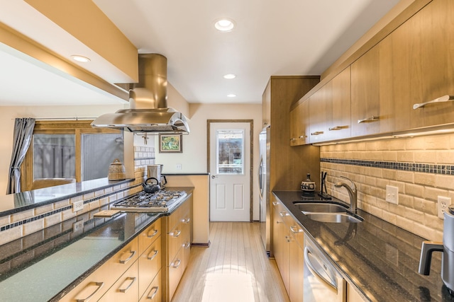 kitchen featuring sink, stainless steel appliances, island range hood, decorative backsplash, and dark stone counters