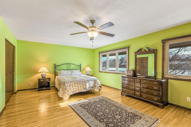 bedroom with ceiling fan, a textured ceiling, and light wood-type flooring