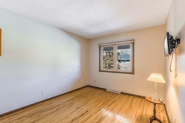 spare room featuring light hardwood / wood-style flooring and a textured ceiling