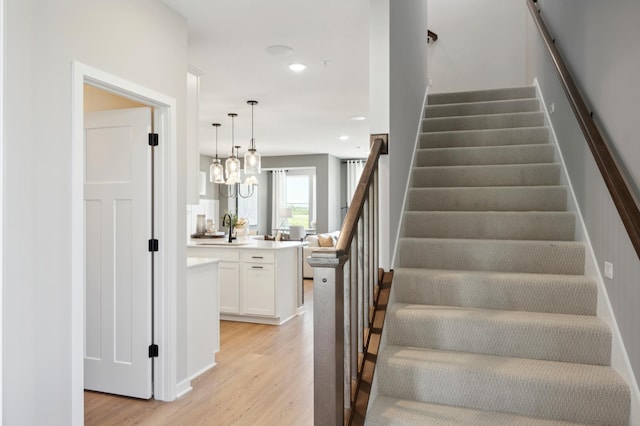 stairs featuring wood-type flooring and sink