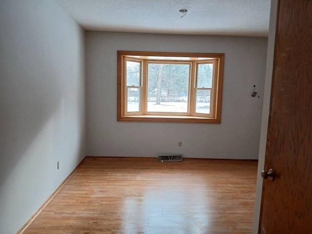 unfurnished room with light hardwood / wood-style flooring and a textured ceiling