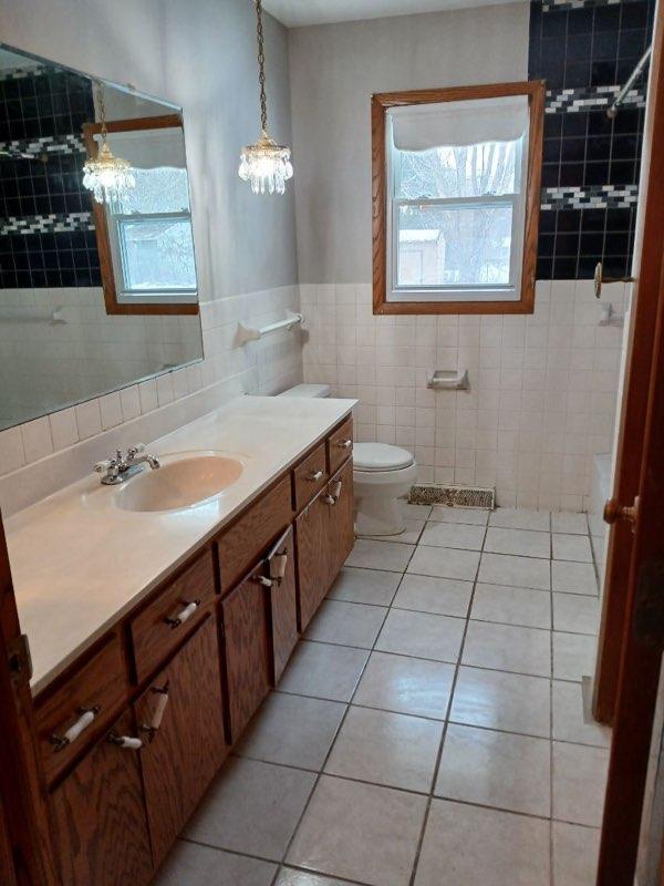 bathroom featuring toilet, tile patterned flooring, tile walls, and vanity