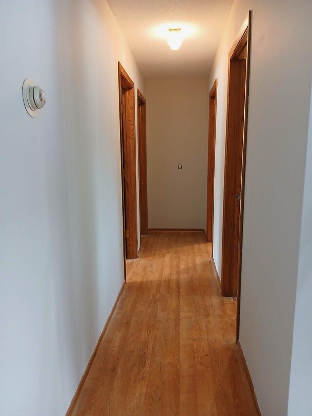 hall with light wood-style flooring and baseboards