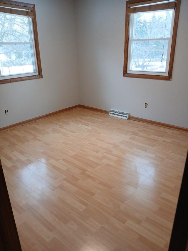 spare room with light wood-style floors, visible vents, and baseboards