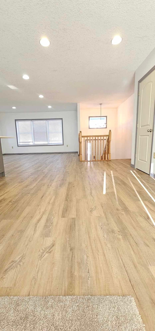 spare room with a healthy amount of sunlight, a textured ceiling, and light wood-type flooring