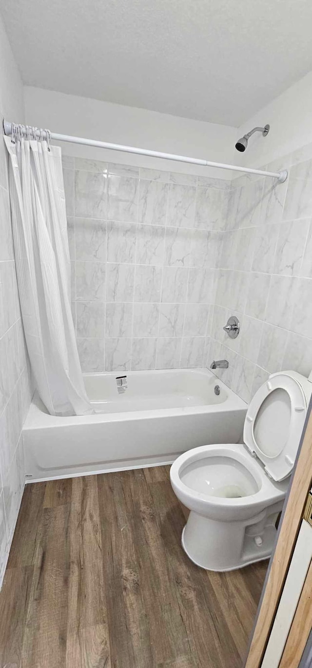 bathroom with wood-type flooring, shower / bath combination with curtain, and toilet