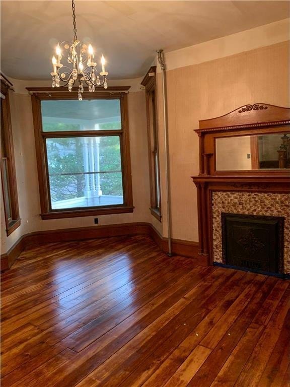 unfurnished dining area with a tile fireplace, dark hardwood / wood-style flooring, and a notable chandelier