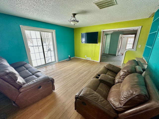 living room with a wealth of natural light, light hardwood / wood-style flooring, and a textured ceiling