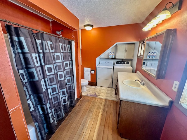 bathroom with washer and clothes dryer, vanity, toilet, a textured ceiling, and wood-type flooring