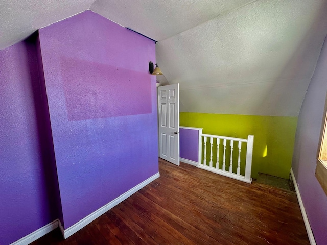 additional living space featuring lofted ceiling, a textured ceiling, and hardwood / wood-style flooring