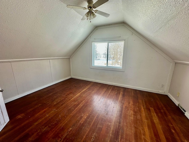 additional living space featuring a textured ceiling, dark hardwood / wood-style flooring, vaulted ceiling, and ceiling fan