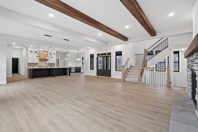 unfurnished living room featuring a fireplace, light hardwood / wood-style floors, and beamed ceiling