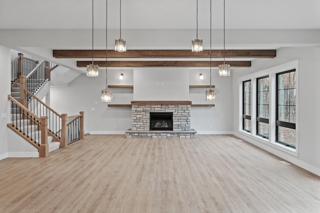 unfurnished living room featuring lofted ceiling with beams, a fireplace, and light hardwood / wood-style floors