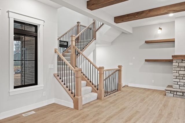 stairway featuring hardwood / wood-style floors and vaulted ceiling with beams