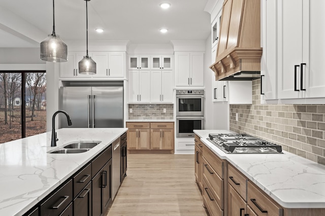 kitchen with light stone countertops, appliances with stainless steel finishes, sink, pendant lighting, and white cabinets