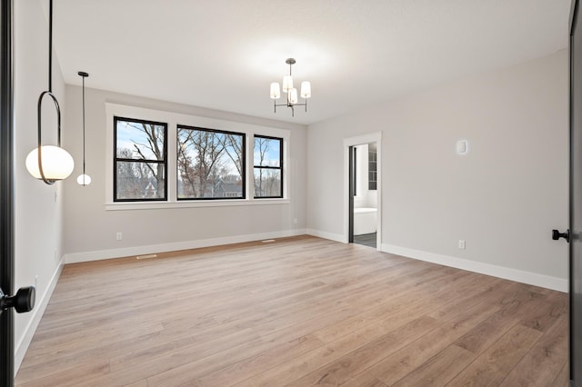 empty room featuring light wood-type flooring and a notable chandelier