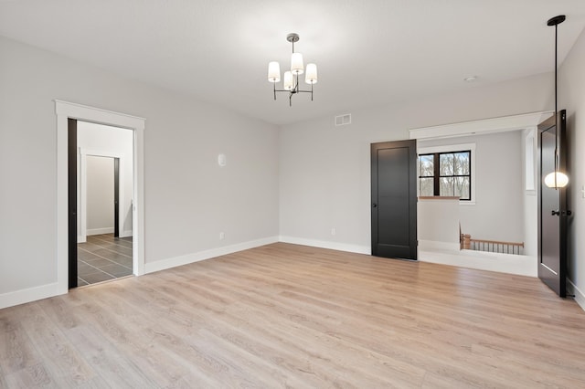 unfurnished room with a chandelier and light hardwood / wood-style floors