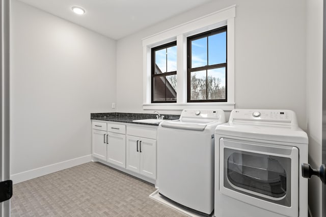 clothes washing area featuring cabinets, sink, and washing machine and clothes dryer