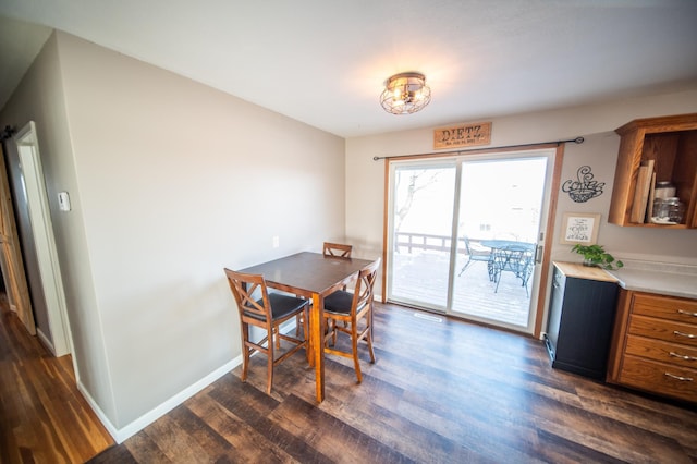 dining area with dark wood-type flooring and an inviting chandelier