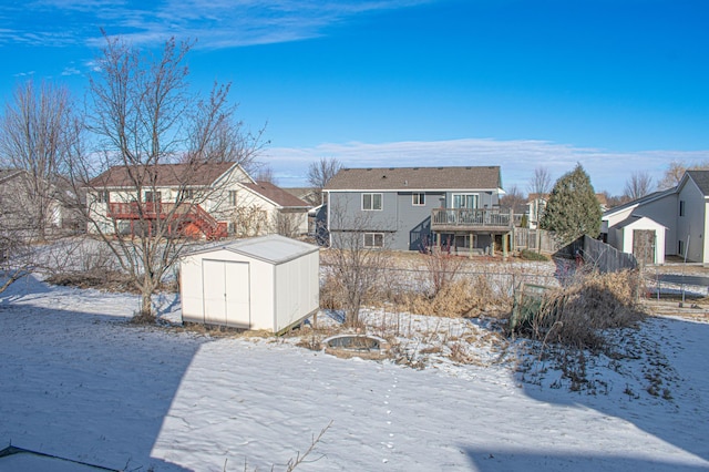 yard layered in snow featuring a trampoline, a deck, and a storage unit