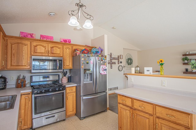 kitchen with lofted ceiling, sink, appliances with stainless steel finishes, hanging light fixtures, and a notable chandelier