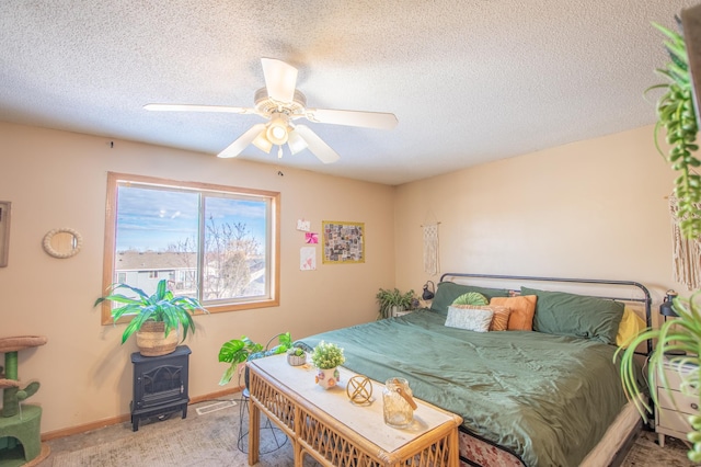 carpeted bedroom featuring ceiling fan, a textured ceiling, and a wood stove