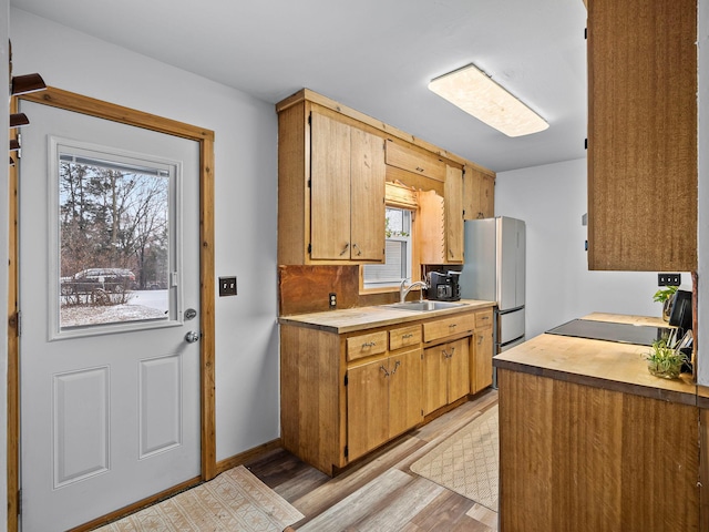 kitchen featuring a healthy amount of sunlight, light wood-type flooring, sink, and stainless steel refrigerator