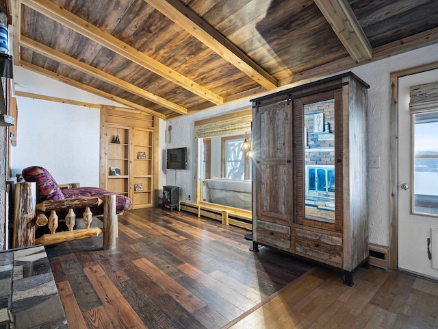 living area featuring baseboard heating, vaulted ceiling with beams, hardwood / wood-style flooring, and a barn door