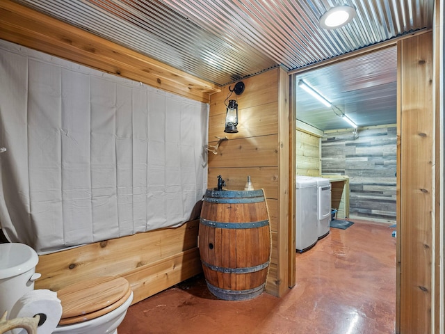 bathroom with concrete floors, toilet, and wood walls