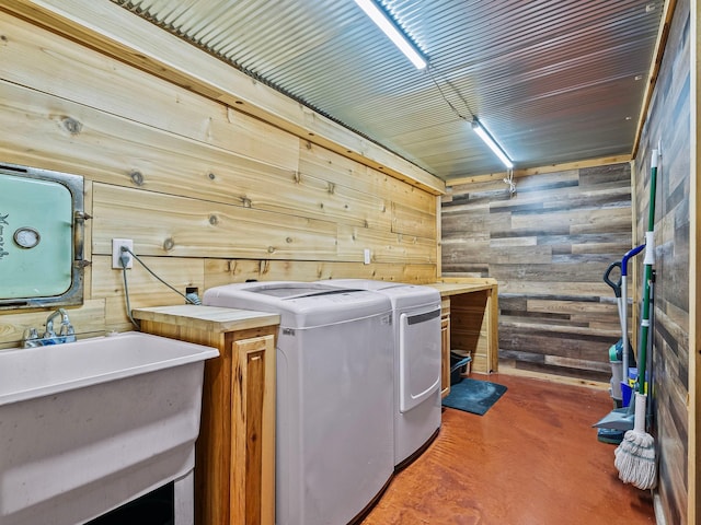 laundry room with cabinets, sink, wooden walls, and washing machine and clothes dryer