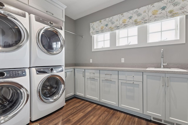 laundry area featuring sink, cabinets, stacked washer / drying machine, and dark hardwood / wood-style flooring