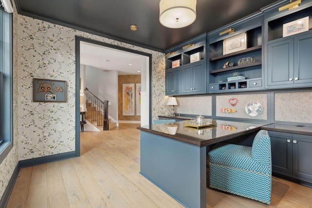 kitchen featuring light hardwood / wood-style floors, kitchen peninsula, ornamental molding, a breakfast bar, and blue cabinets