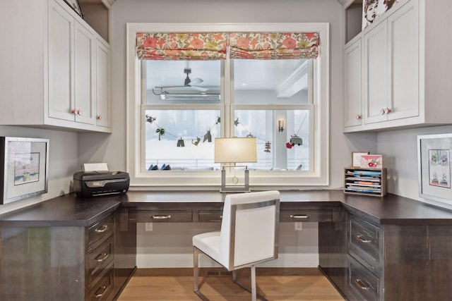 home office with ceiling fan, built in desk, and light wood-type flooring