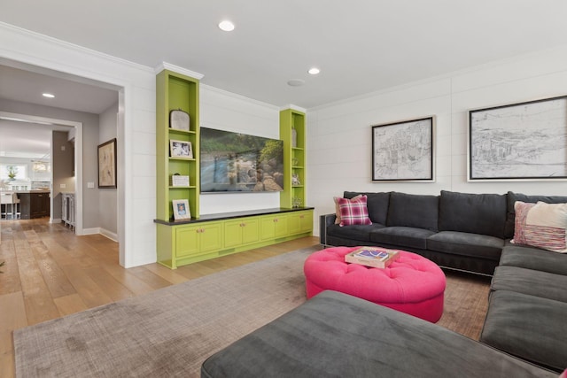 living room featuring built in features, light wood-type flooring, and ornamental molding