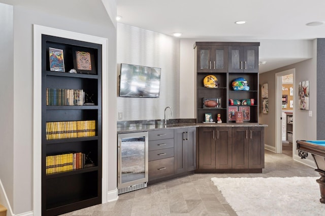 bar featuring dark brown cabinets, built in shelves, beverage cooler, and sink