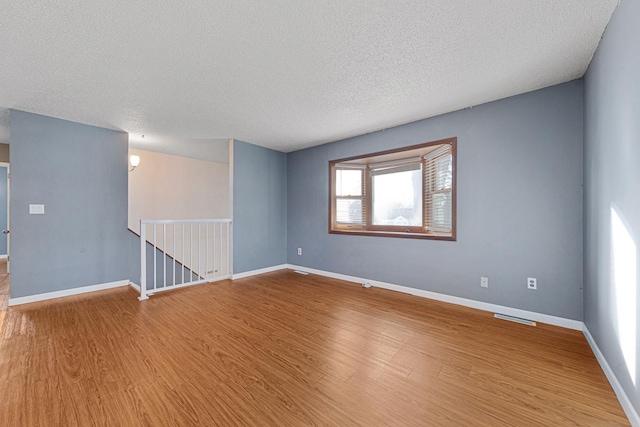 unfurnished room with hardwood / wood-style floors and a textured ceiling