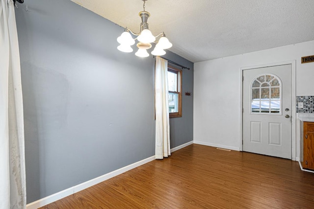 entrance foyer with hardwood / wood-style flooring, a textured ceiling, a wealth of natural light, and an inviting chandelier