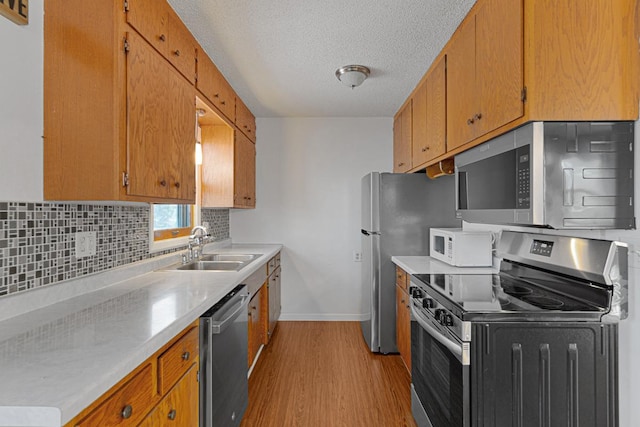 kitchen with tasteful backsplash, light hardwood / wood-style floors, sink, a textured ceiling, and stainless steel appliances