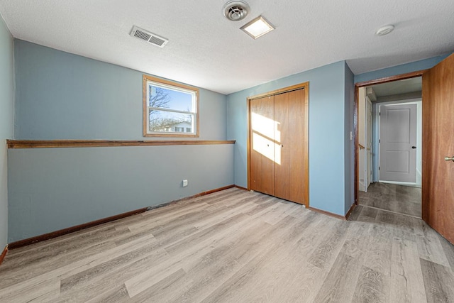 unfurnished bedroom with light wood-type flooring, a closet, and a textured ceiling