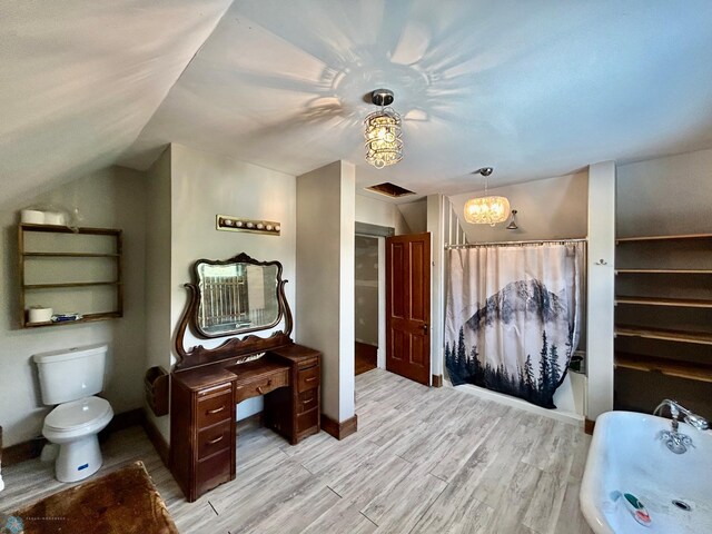 bathroom featuring a bath, vaulted ceiling, toilet, wood-type flooring, and a chandelier