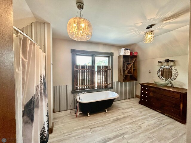 sitting room with a chandelier, lofted ceiling, and light wood-type flooring