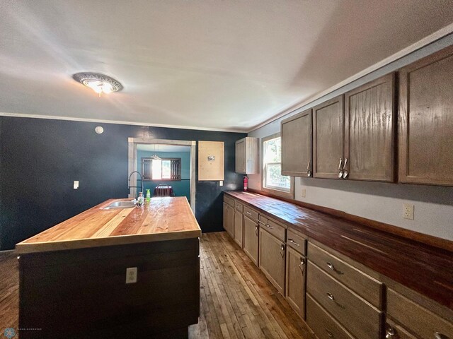 kitchen featuring a center island with sink, ornamental molding, sink, and wooden counters