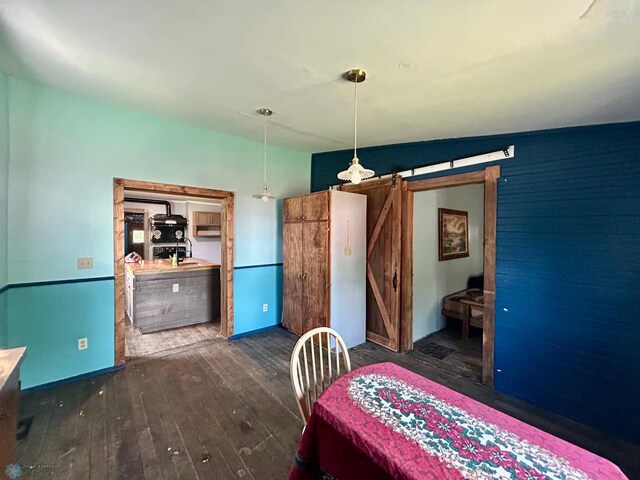 bedroom featuring a barn door, dark wood-type flooring, and vaulted ceiling