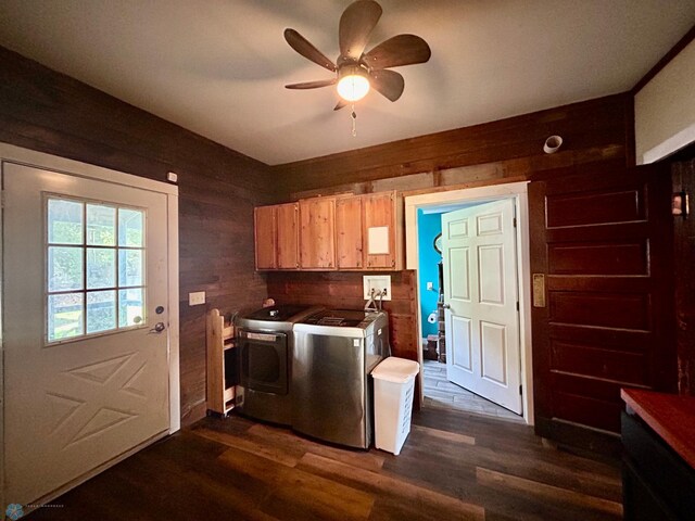 laundry area with cabinets, wooden walls, ceiling fan, separate washer and dryer, and dark hardwood / wood-style flooring