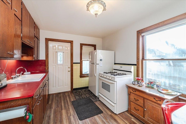 kitchen featuring white appliances, dark hardwood / wood-style floors, sink, and tile walls