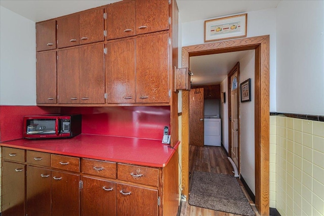 kitchen with hardwood / wood-style flooring, washer / dryer, and tile walls