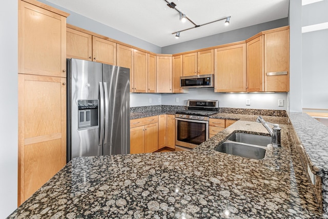 kitchen featuring kitchen peninsula, appliances with stainless steel finishes, dark stone counters, sink, and light brown cabinets