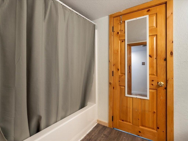 bathroom with shower / tub combo with curtain, hardwood / wood-style flooring, and a textured ceiling