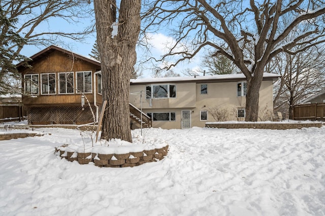 snow covered house featuring a sunroom